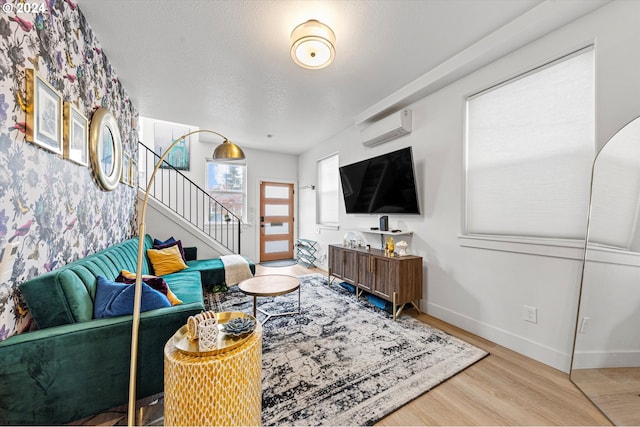 living room with hardwood / wood-style floors, a textured ceiling, and a wall mounted air conditioner