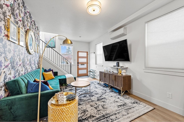 living room with a wall unit AC, hardwood / wood-style flooring, and a textured ceiling