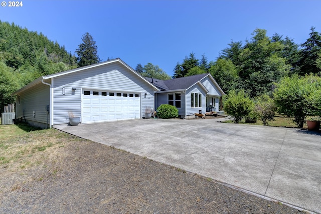 single story home with central AC unit and a garage