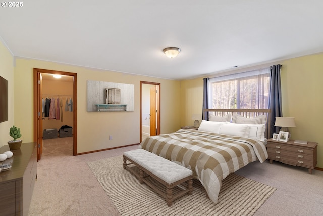 carpeted bedroom featuring a spacious closet, a closet, and ensuite bath