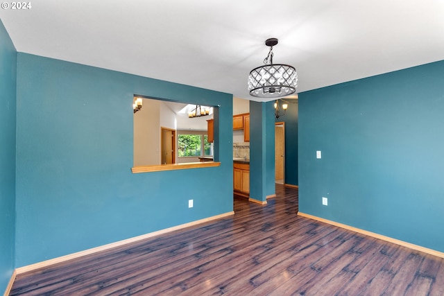 spare room with an inviting chandelier and dark hardwood / wood-style flooring