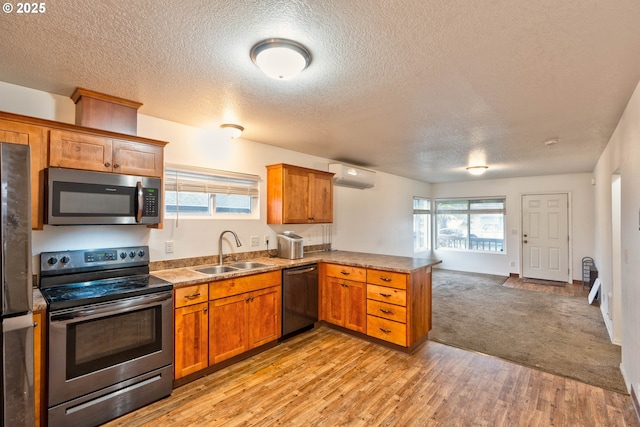 kitchen with sink, stainless steel appliances, kitchen peninsula, a wall mounted AC, and light carpet