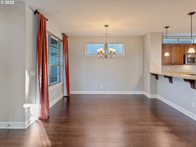 unfurnished dining area with a notable chandelier and dark hardwood / wood-style flooring