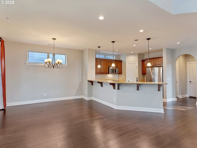 kitchen featuring hanging light fixtures, appliances with stainless steel finishes, a breakfast bar area, and kitchen peninsula