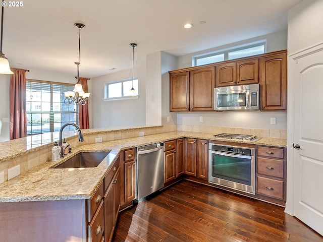 kitchen featuring pendant lighting, appliances with stainless steel finishes, kitchen peninsula, and sink