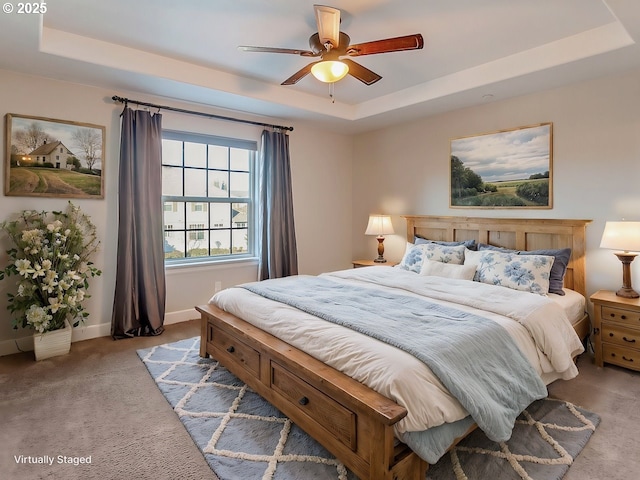 bedroom featuring ceiling fan, light colored carpet, and a tray ceiling