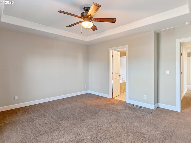 unfurnished bedroom featuring ensuite bathroom, light carpet, ceiling fan, and a tray ceiling