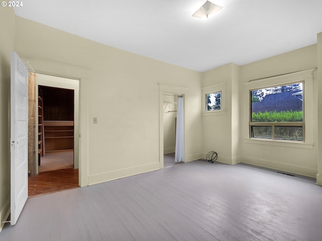 unfurnished bedroom featuring a walk in closet, hardwood / wood-style flooring, and a closet