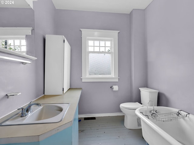 bathroom featuring a tub to relax in, toilet, hardwood / wood-style flooring, and vanity