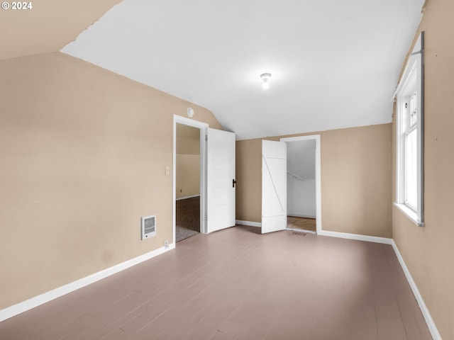 unfurnished bedroom with lofted ceiling, a closet, and hardwood / wood-style flooring