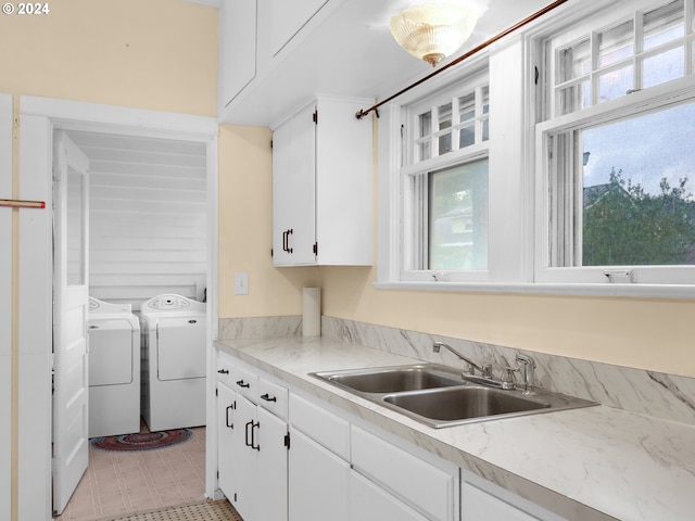 kitchen featuring a healthy amount of sunlight, washing machine and clothes dryer, white cabinetry, and light tile patterned flooring