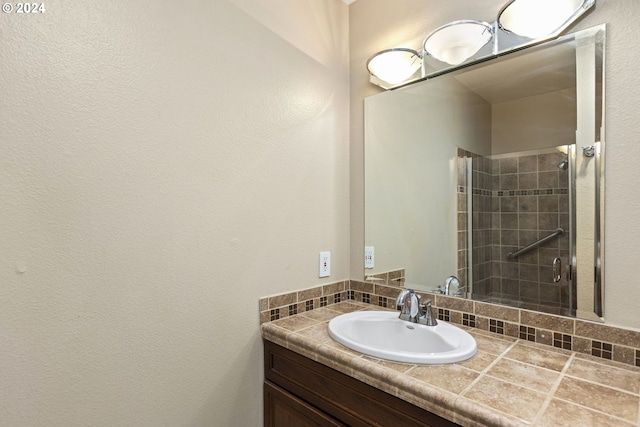 bathroom with vanity, a shower with shower door, and backsplash