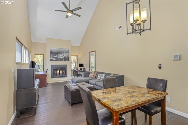 dining area featuring dark wood-type flooring, ceiling fan with notable chandelier, and high vaulted ceiling