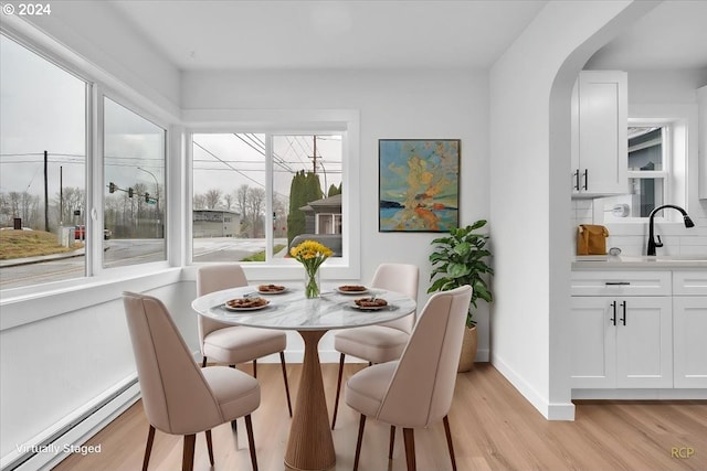 dining room featuring light hardwood / wood-style floors, sink, and a baseboard heating unit