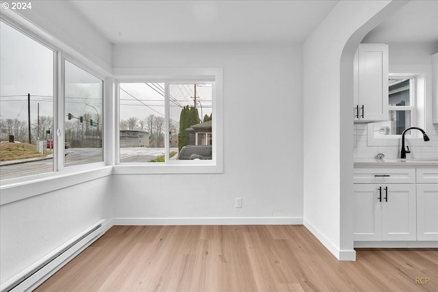 unfurnished dining area featuring light hardwood / wood-style flooring, sink, and a baseboard radiator