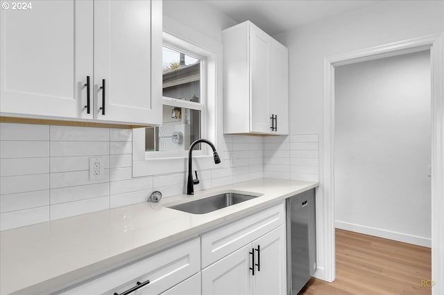 kitchen featuring tasteful backsplash, sink, light hardwood / wood-style flooring, dishwasher, and white cabinetry