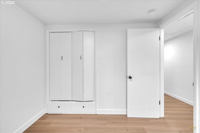 unfurnished bedroom featuring light hardwood / wood-style flooring and a closet