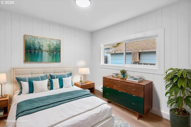 bedroom with light hardwood / wood-style floors and wooden walls