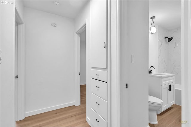 bathroom with tiled shower, vanity, wood-type flooring, and toilet