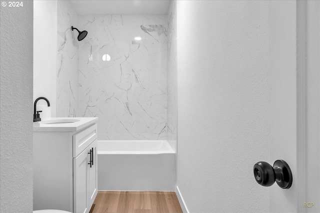 bathroom with vanity, wood-type flooring, and tiled shower / bath