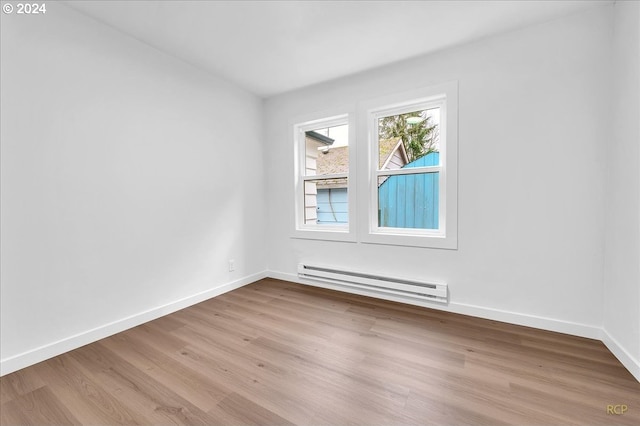 empty room featuring baseboard heating and light hardwood / wood-style flooring