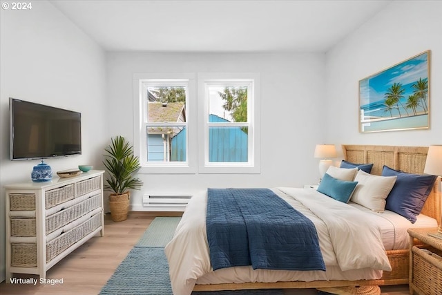 bedroom featuring light hardwood / wood-style flooring and a baseboard heating unit