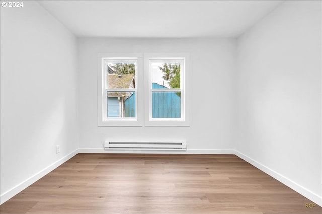 unfurnished room featuring light hardwood / wood-style floors and a baseboard heating unit