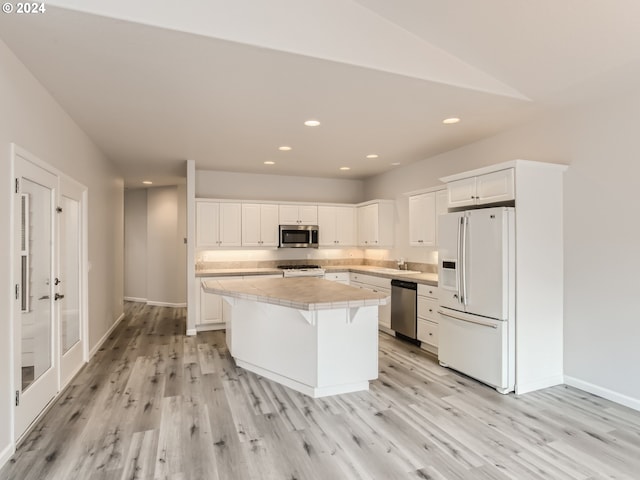 kitchen with stainless steel appliances, a center island, white cabinets, and light hardwood / wood-style floors