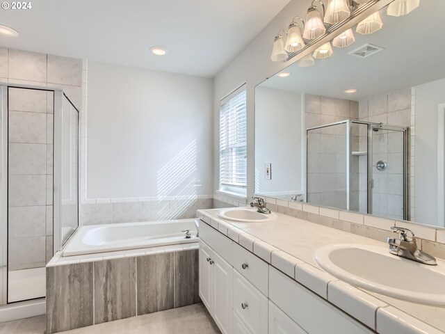 bathroom with double vanity and separate shower and tub