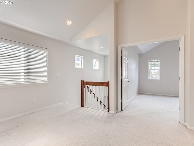 carpeted empty room featuring vaulted ceiling