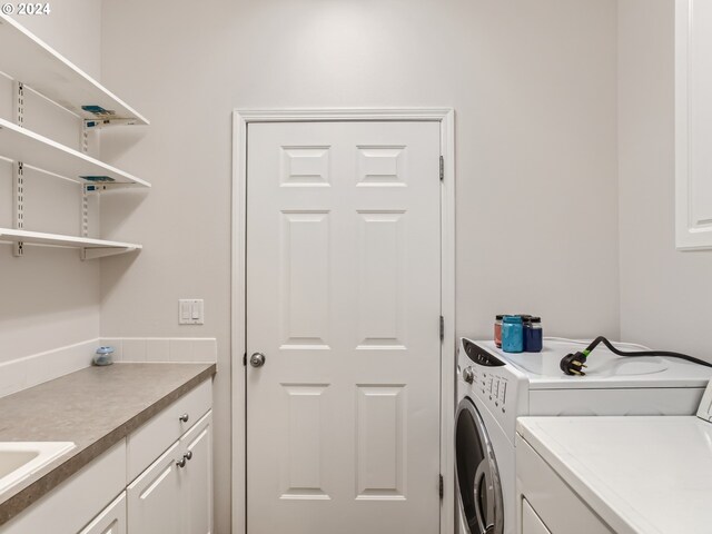 laundry area with washing machine and clothes dryer and cabinets