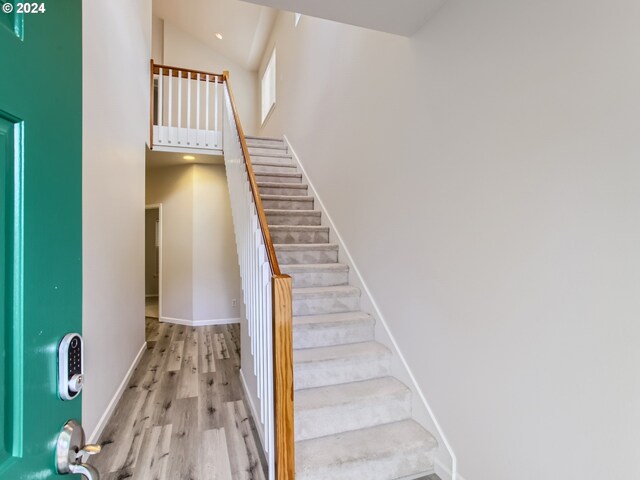 stairway featuring a towering ceiling and wood-type flooring