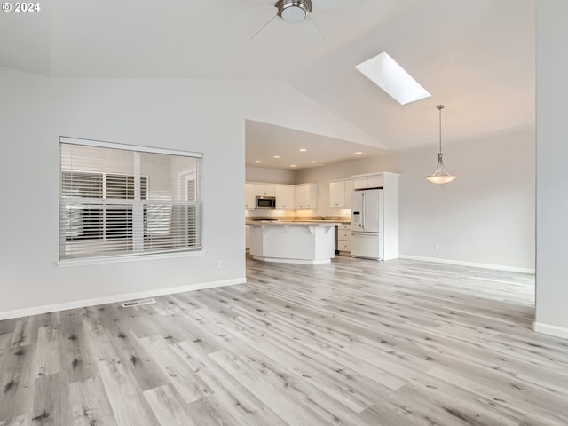 unfurnished living room featuring ceiling fan, light hardwood / wood-style floors, and vaulted ceiling with skylight