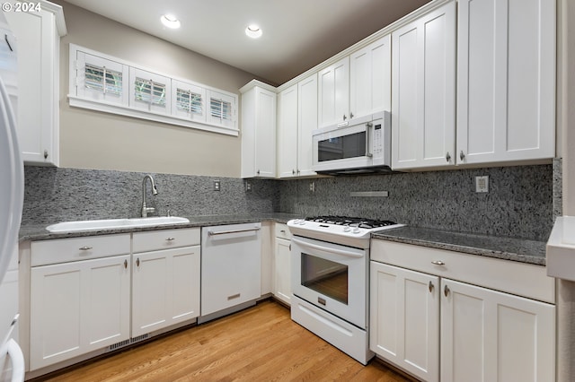 kitchen with white cabinets, white appliances, light hardwood / wood-style floors, and backsplash