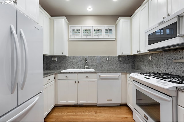 kitchen with light wood-type flooring, tasteful backsplash, white appliances, sink, and white cabinets