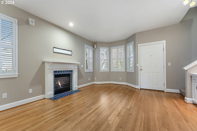 unfurnished living room with a fireplace, light hardwood / wood-style flooring, and a healthy amount of sunlight