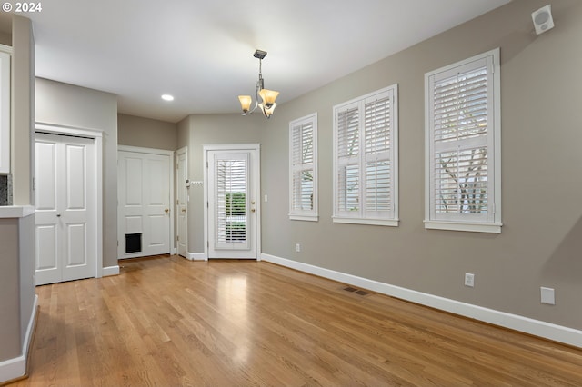 interior space with light wood-type flooring and an inviting chandelier