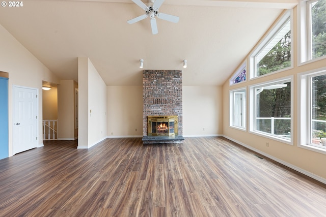 unfurnished living room with hardwood / wood-style floors, a brick fireplace, beam ceiling, high vaulted ceiling, and brick wall