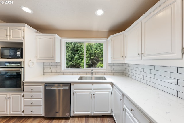 kitchen with sink, appliances with stainless steel finishes, hardwood / wood-style floors, and white cabinetry