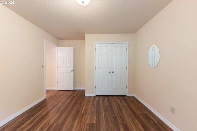 unfurnished bedroom with dark hardwood / wood-style floors, a closet, and a textured ceiling