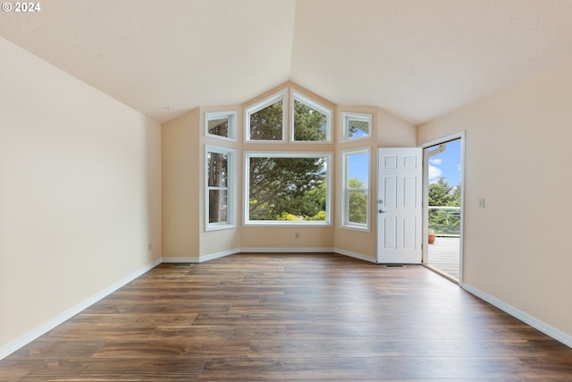 empty room with a healthy amount of sunlight, lofted ceiling, and hardwood / wood-style floors