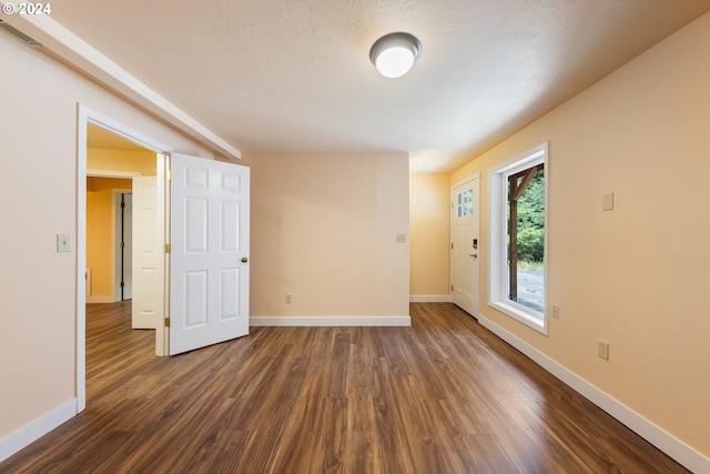 unfurnished room with dark hardwood / wood-style flooring and a textured ceiling