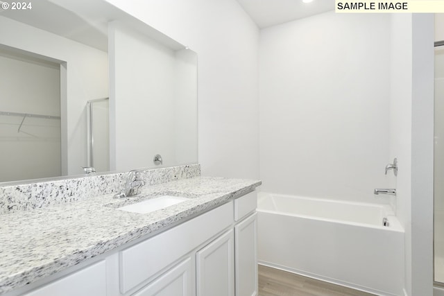 bathroom with plus walk in shower, wood-type flooring, and vanity