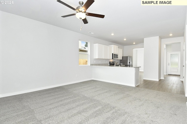 unfurnished living room featuring light carpet and ceiling fan