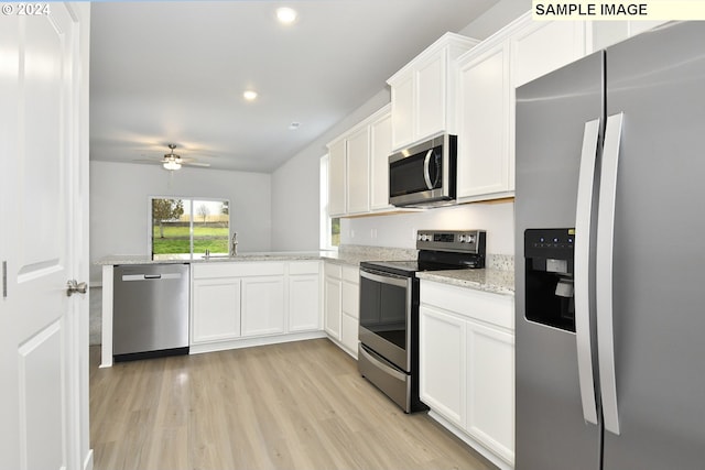 kitchen with light wood-type flooring, light stone counters, stainless steel appliances, ceiling fan, and white cabinets