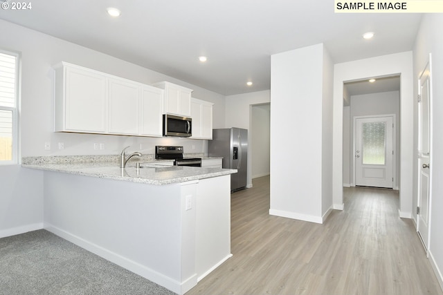 kitchen with kitchen peninsula, stainless steel appliances, and white cabinetry