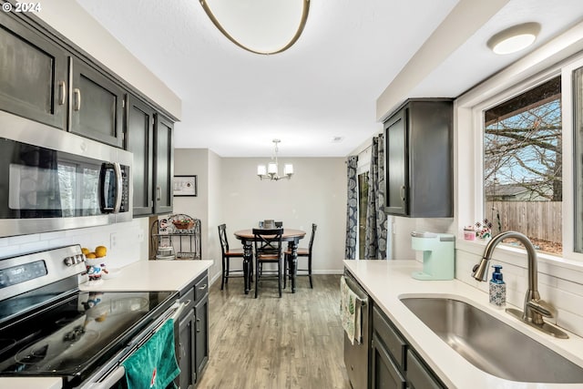 4711 Siesta Ct NE, Salem, OR 97305 - kitchen featuring sink, hanging light fixtures, stainless steel appliances, an inviting chandelier, and light wood-type flooring