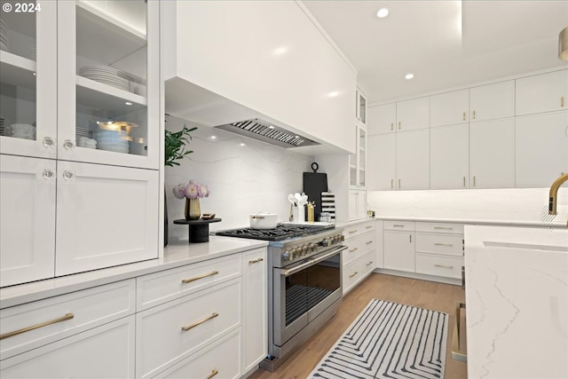 kitchen with light hardwood / wood-style floors, white cabinets, decorative backsplash, double oven range, and light stone countertops