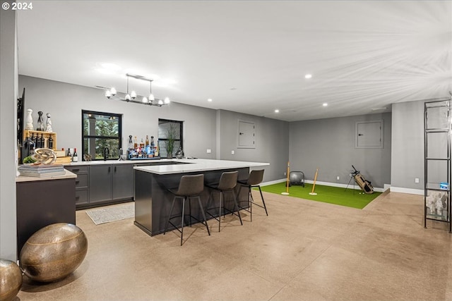 interior space featuring hanging light fixtures, a kitchen island, gray cabinetry, a breakfast bar, and an inviting chandelier