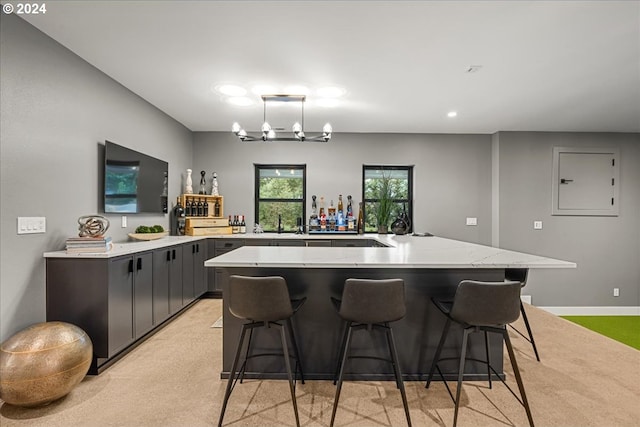 kitchen with hanging light fixtures, sink, a breakfast bar, light carpet, and an inviting chandelier